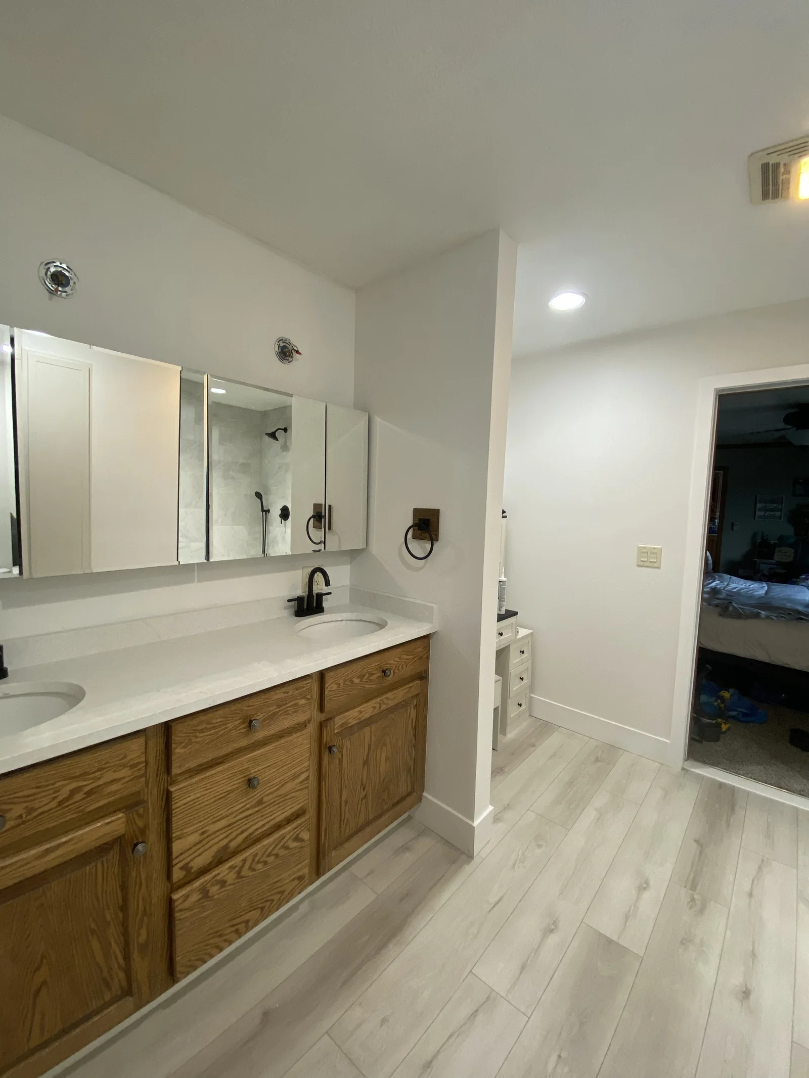 Wood vanity with white countertop and illuminated mirror