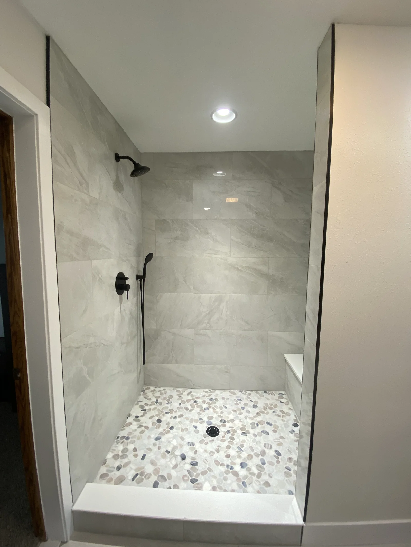 Walk-in shower with grey tile walls and mosaic shower floor