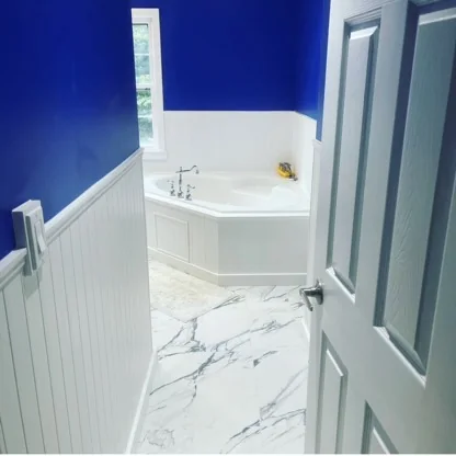 Blue bathroom with white wainscoting and marble-look floor