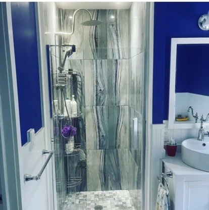 Glass shower enclosure beside blue bathroom walls