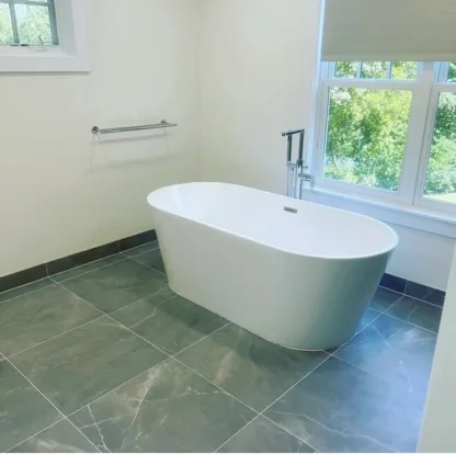 Freestanding tub beside windows and large-format floor tile