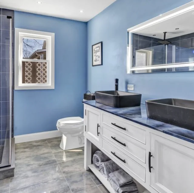 Blue bathroom with double vanity and dark vessel sinks