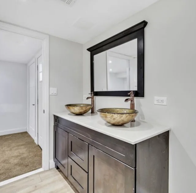 Bathroom with wood vanity, vessel sink and dark-framed mirror