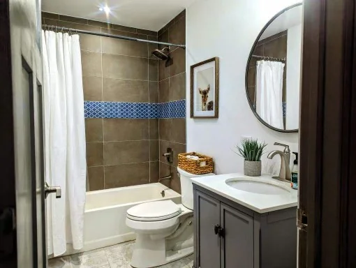 Bathroom with glass tub enclosure and dark vanity